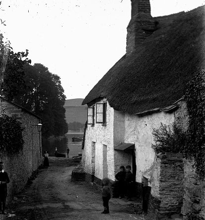 'Shadycombe, Salcombe. No. 221'. View down lane, past cottages and across the estuary. Small boys on porch, other bystanders. '
