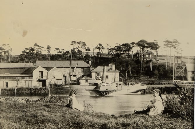 Around 1900 - 1905. Bonds Quay, Kingsbridge, from west bank of estuary, with paddle steamer 'Express' berthed in background. Two children in foreground.  Napoleonic war barracks in right background.